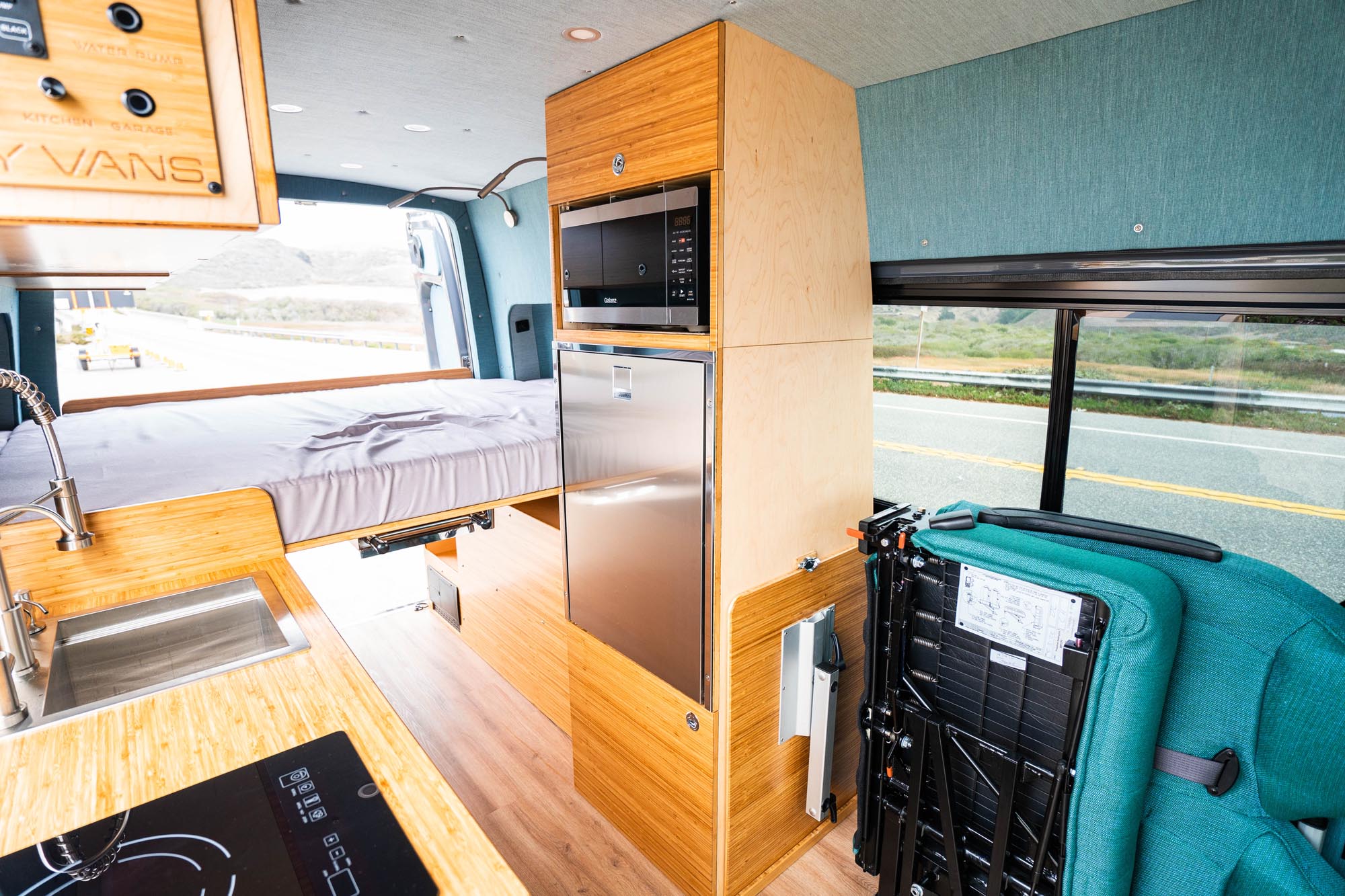 luxury van conversion with bamboo cabinetry, platform bed folding bench seat induction cooktop
